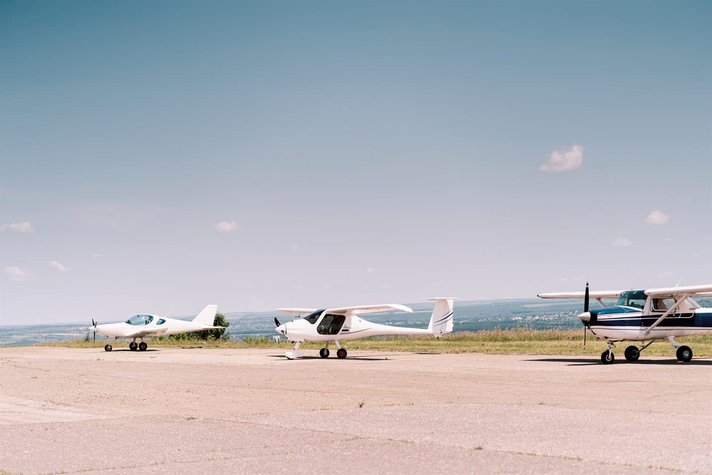 Light aircraft parked on an airfield under a clear sky.