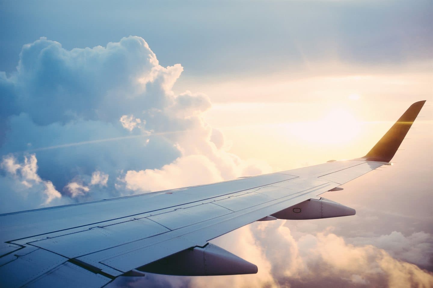 An aircraft wing above the clouds at sunrise.